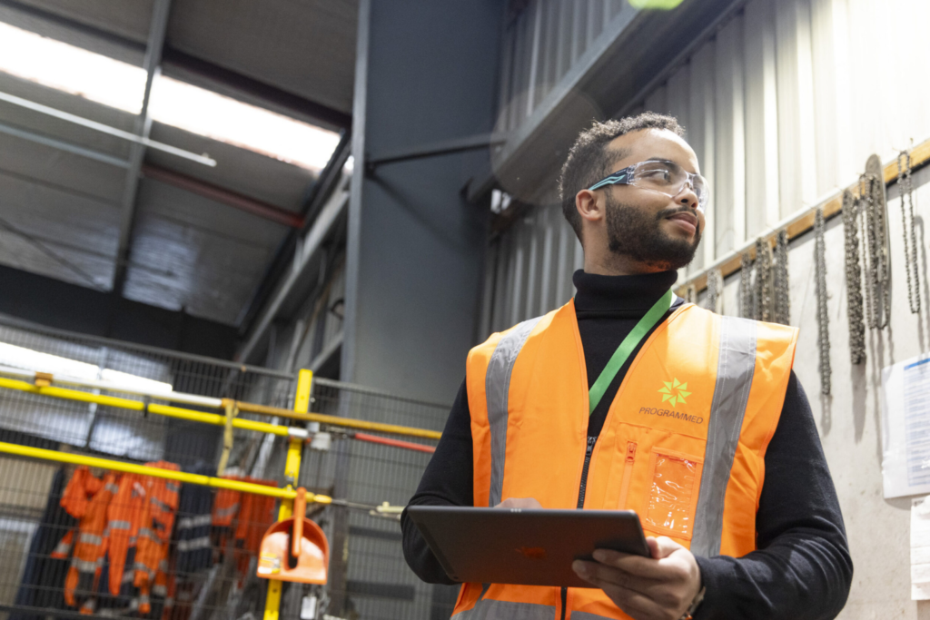 man in high-ves vest and safety glasses in a factory